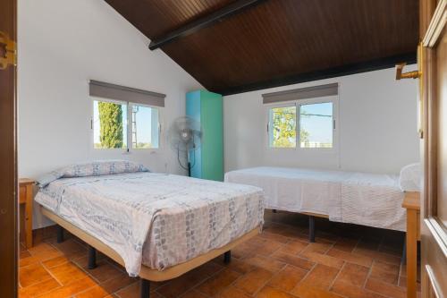 two beds in a room with two windows at Valle Verde in Morón de la Frontera