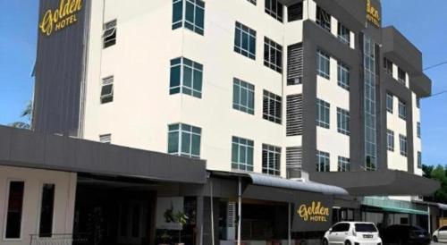a large white building with a car parked in front of it at Golden Hotel in Kota Kinabalu