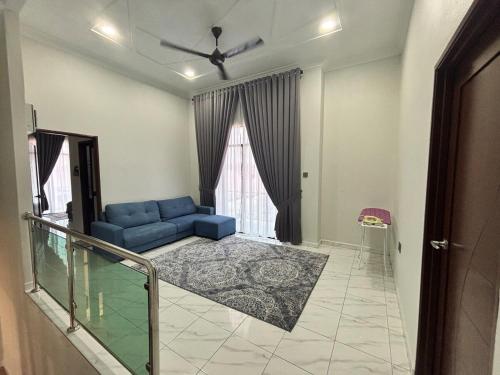 a living room with a blue couch in front of a window at Danish Villa in Kota Bharu