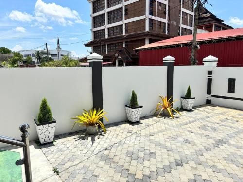 a white fence with potted plants on a patio at Danish Villa in Kota Bharu