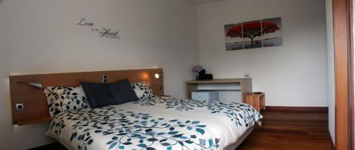 Schlafzimmer mit einem Bett mit einer blauen und weißen Bettdecke in der Unterkunft Casa Os Manos in Santana