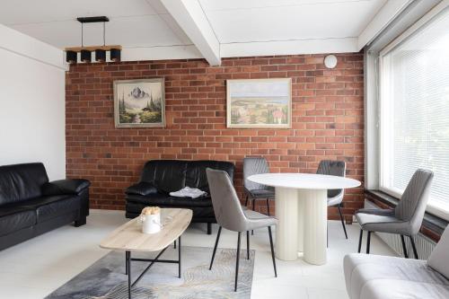 un soggiorno con muro di mattoni, tavolo e sedie di Kotimaailma Rooms - Ankkuri 2hh a Kotka