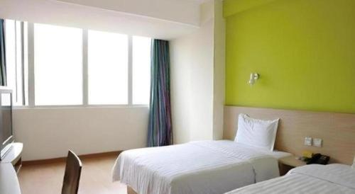 a hotel room with two beds and a green wall at 7 Days Inn Changchun Zhengyang Street Changchun Park Branch in Changchun