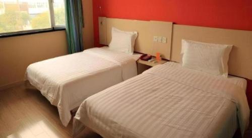 two beds in a hotel room with red walls at 7 Days Inn Changchun Zhengyang Street Changchun Park Branch in Changchun
