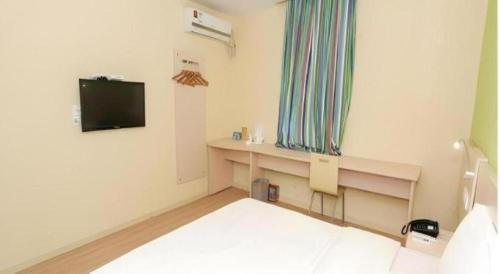 a room with a bed and a desk with a television at 7 Days Inn Changchun Zhengyang Street Changchun Park Branch in Changchun