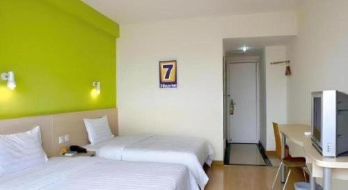a room with two beds and a desk and a television at 7 Days Inn Changchun Zhengyang Street Changchun Park Branch in Changchun