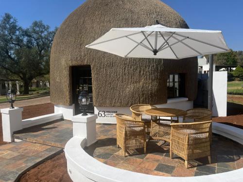 a table and chairs with an umbrella in front of a building at Kievits Kroon Gauteng Wine Estate in Pretoria