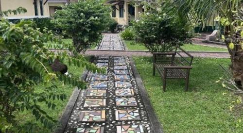 a garden with a path with a table and benches at New Dawn For Langkawi in Pantai Cenang