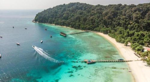 an aerial view of a beach with a boat in the water at New Dawn For Langkawi in Pantai Cenang