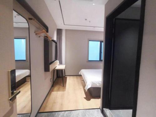 a small room with a bed and a mirror at GreenTree Inn Datong YundinGYAyuan Express Hotel in Datong