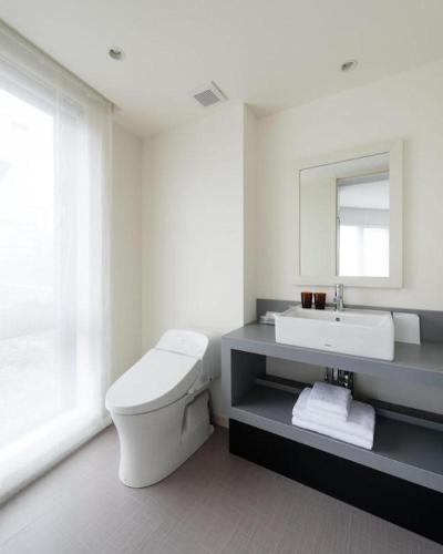 a white bathroom with a toilet and a sink at Hotel Edit Yokohama in Yokohama