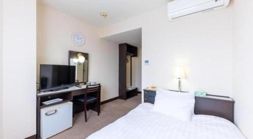 a bedroom with a bed and a desk with a television at Tabist Hotel New Osamura Sabae in Fukui