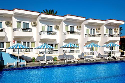 a hotel with chairs and umbrellas next to a swimming pool at Sand Beach Resort in Hurghada