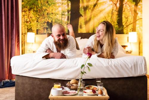 a man and a woman sitting in a bed at Trihotel Rostock - Wellnesshotel Adults Only in Rostock