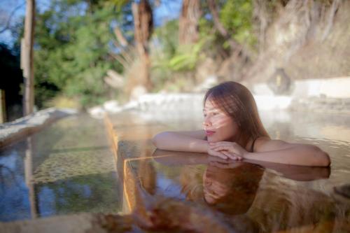 a woman is sitting in a pool of water at Okoroire Hot Springs Hotel in Okoroire
