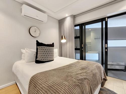 Un dormitorio con una cama con un reloj en la pared. en The Honeycomb on S 2 Bedroom Modern, Secure, Central Apartment, en Vosburg
