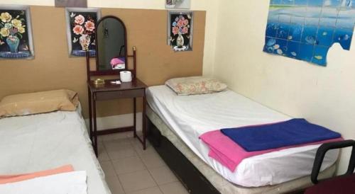 two twin beds in a room with a table and a bed at SPOT ON 90625 Super Green Grass Hotel in Yong Peng