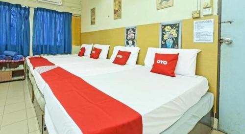 two beds in a room with red and white pillows at SPOT ON 90625 Super Green Grass Hotel in Yong Peng
