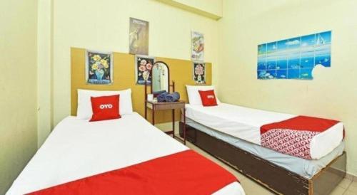 a room with two beds with red and white sheets at SPOT ON 90625 Super Green Grass Hotel in Yong Peng