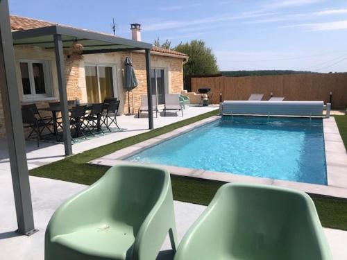 - une piscine avec 2 chaises vertes à côté d'une maison dans l'établissement Villa Mapokia 2 , climatisée, proche Uzès, 3 étoiles de France, à Saint-Marcel-de-Carreiret