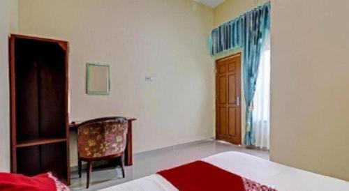 a bedroom with a bed and a chair and a window at OYO 90945 Arizon Kost in Jambi