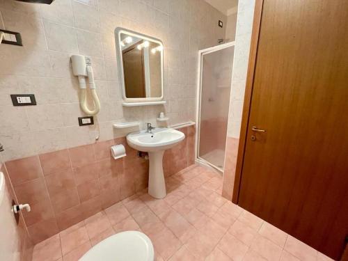 a bathroom with a sink and a toilet and a mirror at Flat in a residence with shared pool in Veneto