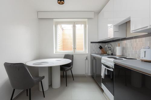 a white kitchen with a small table and chairs at Kotimaailma Aparthotel - Ankkuri - Studio in Kotka