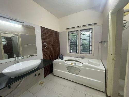 a bathroom with a white tub and a sink and a mirror at Varsha's Nest at Uthandi in Chennai