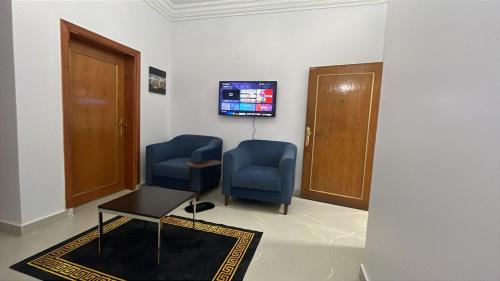 a waiting room with two blue chairs and a tv at شقة راقية للايجار اليومي in Taif