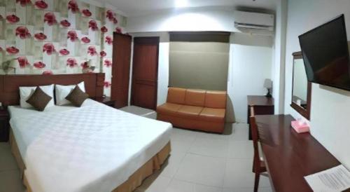 a bedroom with a bed and a desk and a television at Jelita Tanjung Hotel in Tanjung