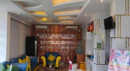 a living room with yellow chairs and a refrigerator at Jelita Tanjung Hotel in Tanjung