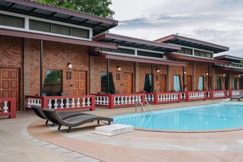 a resort with a pool and a building at Pongphen Guesthouse - SHA Plus Certified in Kanchanaburi