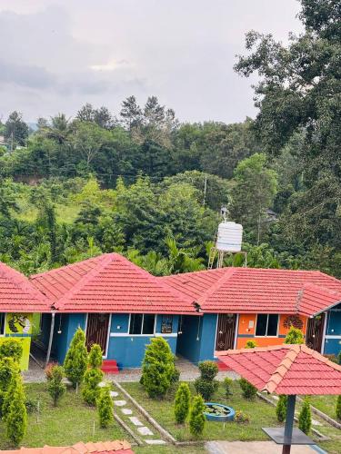 a house with a red roof in front of a forest at Coorg Sunrise Cottage Homestay in Kushālnagar