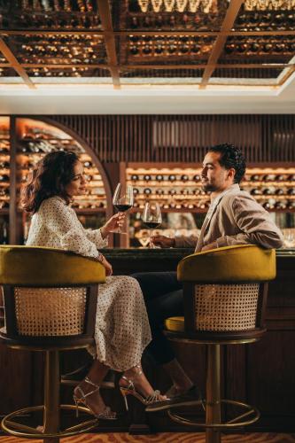 a man and woman sitting at a bar drinking wine at La Maison 20 Degrés Sud - Relais & Châteaux in Grand Baie