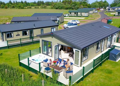 a family sitting on the porch of a modular house at Heathergate Boutique Holiday Park in Hexham