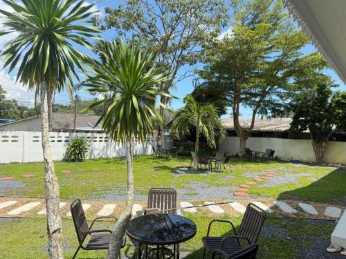 a patio with a table and chairs and palm trees at Three COCO Villa in Ao Nang Beach