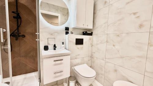 a white bathroom with a toilet and a shower at Apartment Seaside Jelitkowo in Jelitkowo