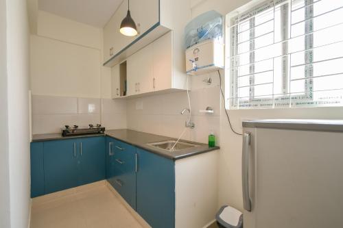 バンガロールにあるHomeSlice Manor, Premium Apartment in Whitefieldの青いキャビネットとシンクのあるキッチン