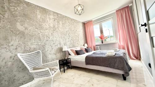 a bedroom with a bed and a chair at Apartment Seaside Jelitkowo in Jelitkowo