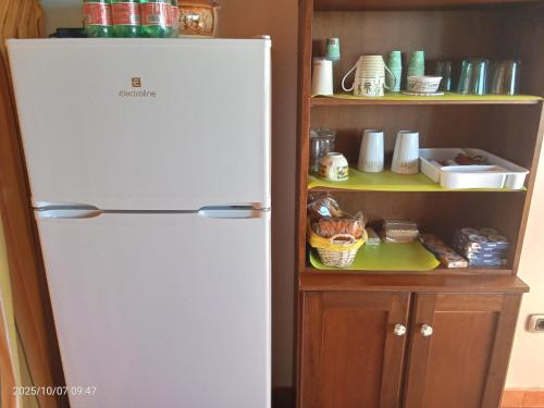 a white refrigerator in a kitchen next to a shelf at Villa Amalia - mansarda in Cinisi