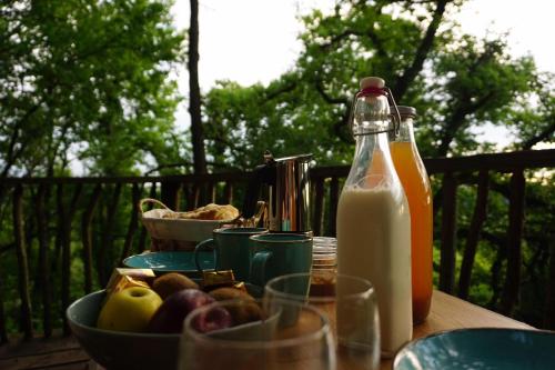 a table with a bowl of fruit and a bottle of milk at Maison Terre Les Cabanes de Fallot - sauna bain-froid piscine naturelle in LʼIsle-Bouzon