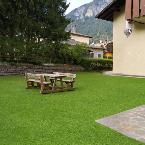 a picnic table and bench on a lawn at Casa Tullia by Go New Location in Ziano di Fiemme