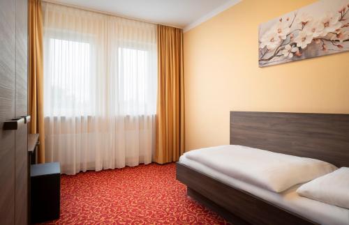 a hotel room with a bed and a window at ates Hotel Lampertheim by AURUM in Lampertheim