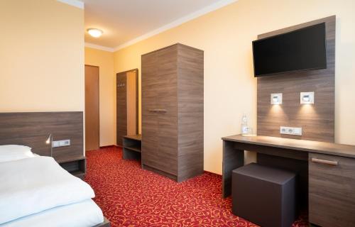 a hotel room with a bed and a desk with a television at ates Hotel Lampertheim by AURUM in Lampertheim