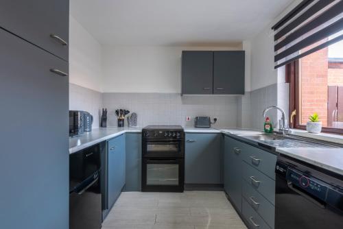 a kitchen with blue cabinets and a stove top oven at Spacious 2br Near Queens Uni & City Centre in Belfast