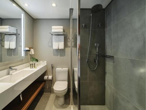 a bathroom with a shower and a toilet and a sink at Grand Mercure SP Itaim Bibi in Sao Paulo