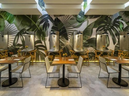 a restaurant with tables and chairs and a mural at Grand Mercure SP Itaim Bibi in Sao Paulo