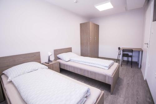 a bedroom with two beds and a desk and a table at Turbo Szálló Kalocsa in Foktő