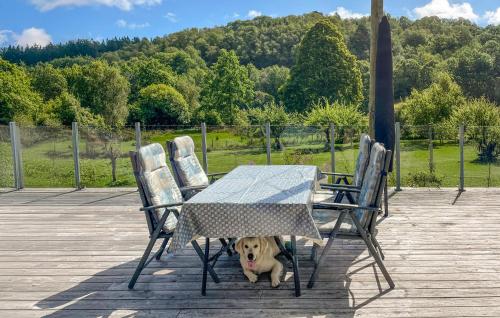 un chien assis sous une table et des chaises dans l'établissement 3 Bedroom Cozy Home In Farsund, à Helle