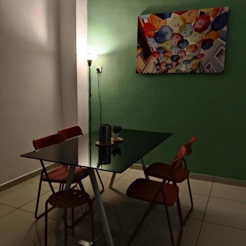 a table and chairs in a room with a green wall at Homestay Payung Merah Islam Sahaja in Simpang Empat